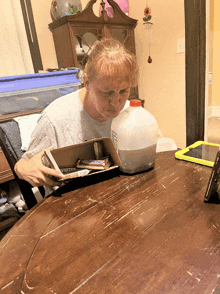 a woman sits at a table looking at a box of snickers