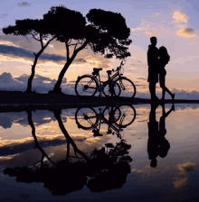 a silhouette of a man and woman standing next to a bike