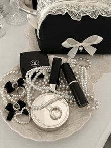 a chanel purse sits next to a plate of pearls and makeup