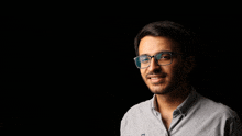 a man wearing glasses and a grey shirt with the letter n on the collar