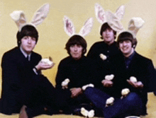 four men wearing bunny ears and holding eggs pose for a photo