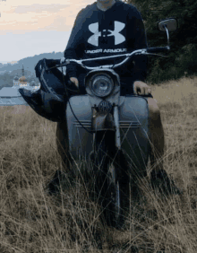 a man wearing a black under armour hoodie is riding a scooter