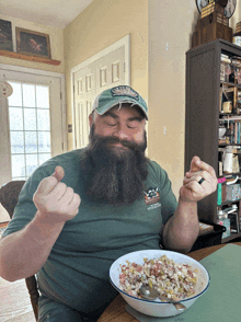 a man with a beard is sitting at a table eating a bowl of food