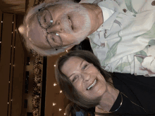 a man and a woman are smiling in front of a crowd in an auditorium