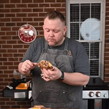 a man in an apron is eating a sandwich with a clock in the background that shows the time as 10:10