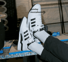 a person is wearing a pair of white adidas shoes