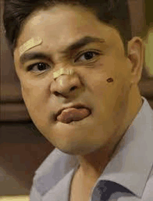 a man with a bandage on his face is making a funny face .