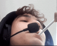 a man wearing headphones and a microphone holds a white stick in his mouth