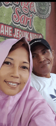 a man and woman are posing for a picture in front of a sign that says " sari "