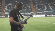 a man playing a guitar on a soccer field with an ad for приватбанк behind him