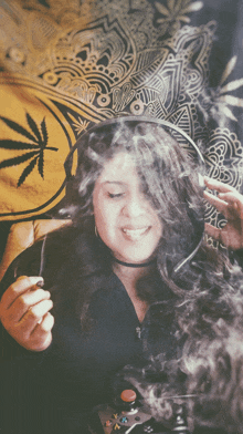 a woman smoking a cigarette in front of a marijuana tapestry