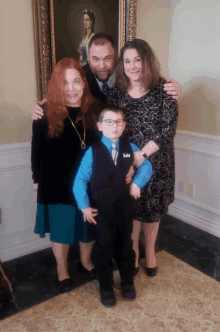 a family poses for a picture in front of a framed portrait