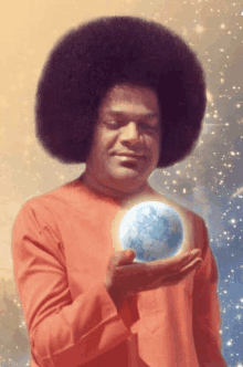 a man with a big afro is holding a glowing globe in his hand