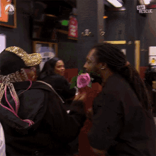 a man is kissing a woman on the cheek while holding a pink rose in front of a sign that says bar rescue