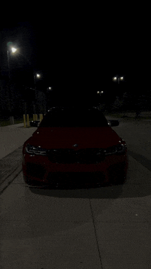 a red car is parked on a sidewalk at night