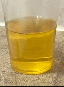 a plastic cup filled with yellow liquid is sitting on a table .