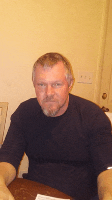 a man with a beard is sitting at a table with a piece of paper on it