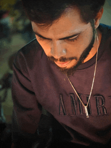 a man with a beard is wearing a sweater that says amiri