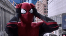 a man in a spiderman costume is holding his head in his hands .