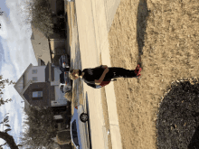 a boy wearing a black shirt that says ' texas ' on it is standing on a sidewalk