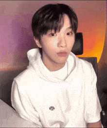 a young man wearing a white hoodie and a white t-shirt is making a funny face .