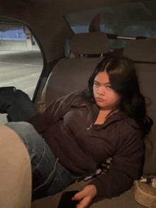 a woman sits in the back seat of a car with a sign that says x on it