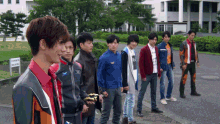 a group of young men are standing in front of a building with a sign that says ' no smoking ' on it