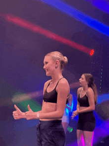 a woman giving a thumbs up in front of a crowd