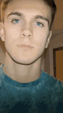 a close up of a young man 's face with a blue shirt on