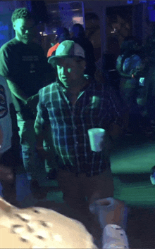 a man in a plaid shirt is holding a cup in a crowd