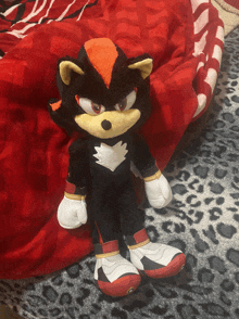 a stuffed animal of shadow the hedgehog laying on a bed