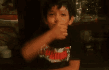 a young boy is making a funny face while wearing a black shirt .