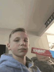 a boy is holding a scrabble board in front of his face