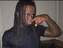 a man with long dreadlocks is holding his nose