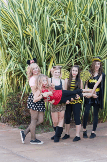 a woman in a minnie mouse costume is being held up by a group of girls