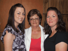 three women posing for a picture with one wearing a red shirt