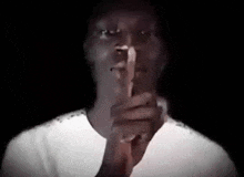 a man is holding his finger to his mouth and making a silence sign .