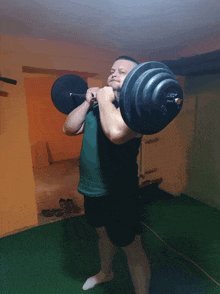 a man in a green shirt is lifting a barbell with the letter a on the end