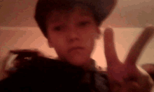 a young boy is giving a peace sign with his fingers