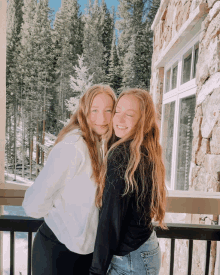 two girls posing for a picture in front of a stone building