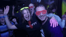 a man and a woman are posing for a picture in a crowd at a party .