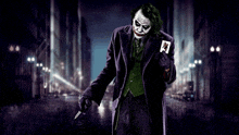 the joker is holding a card and a gun