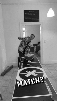 a man standing next to a beerpong table with the words match on it