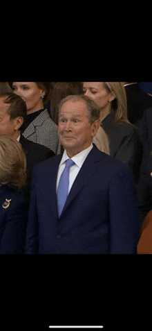 a man in a blue suit and tie is standing in a crowd of people