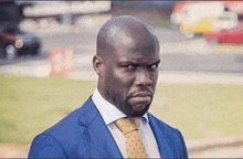 a man in a suit and tie is making a funny face and looking at the camera .