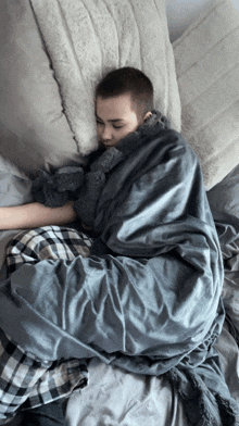 a person wrapped in a grey blanket is sleeping