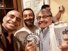 a man holding a can of ol9 beer with two other men