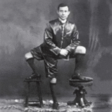 a man in a suit and tie is sitting on a stool .