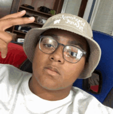 a young man wearing a bucket hat and glasses is making a peace sign