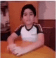 a young boy is sitting at a table in a room .